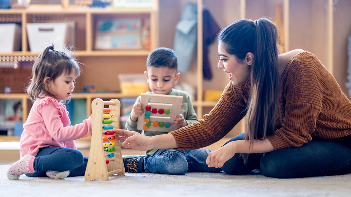 A teacher playing with blocks with two younger children.