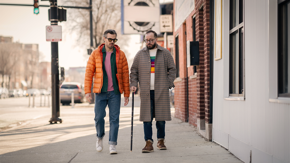 Two men walking down a sidewalk.