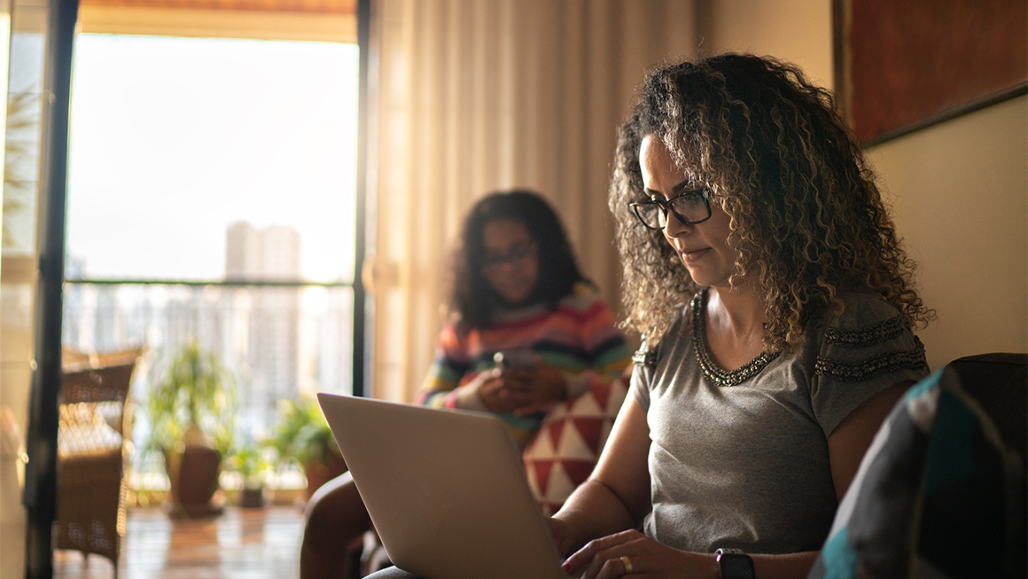 A woman working on her laptop in her living room.
