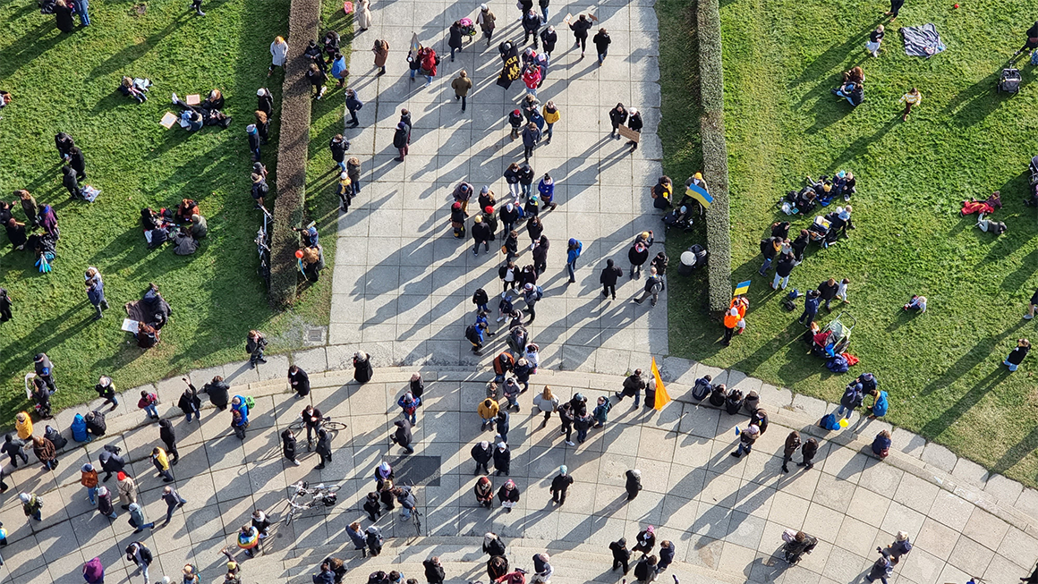 Photo taken from above of dozens of people walking in a park.