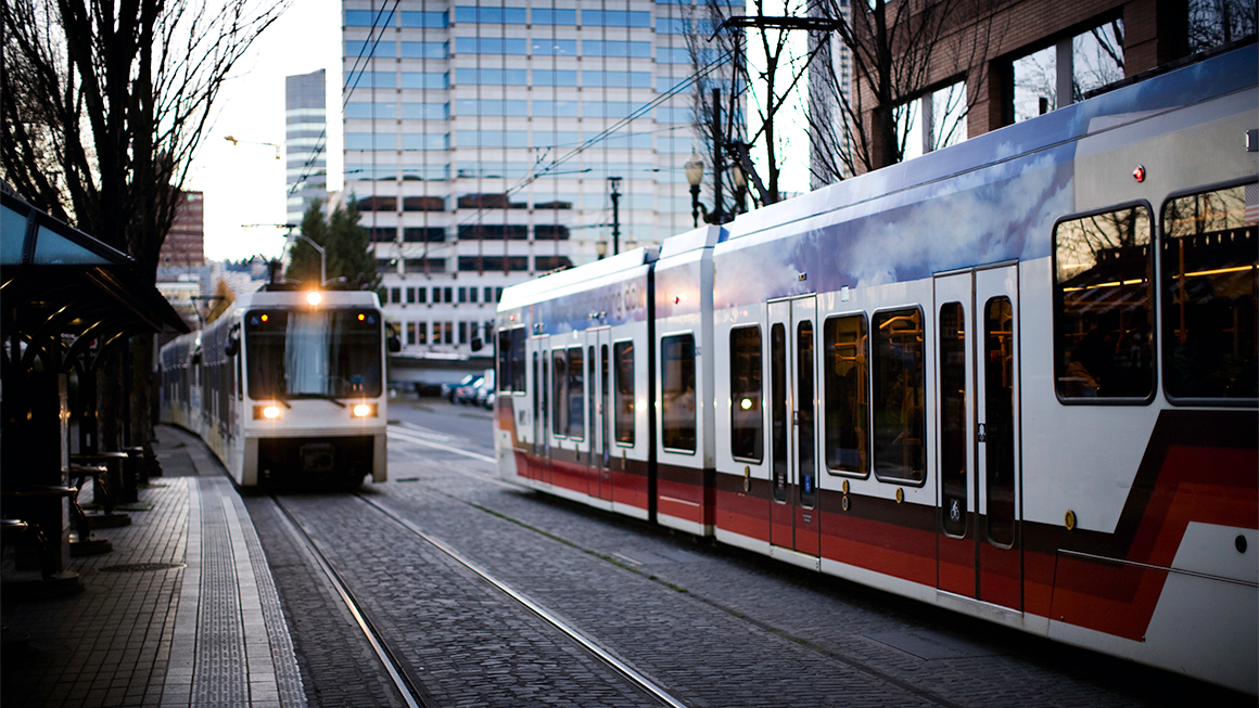 Two public transit trains passing through a city.