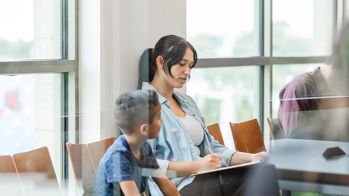 A mother and child in a waiting room for a doctor's visit.
