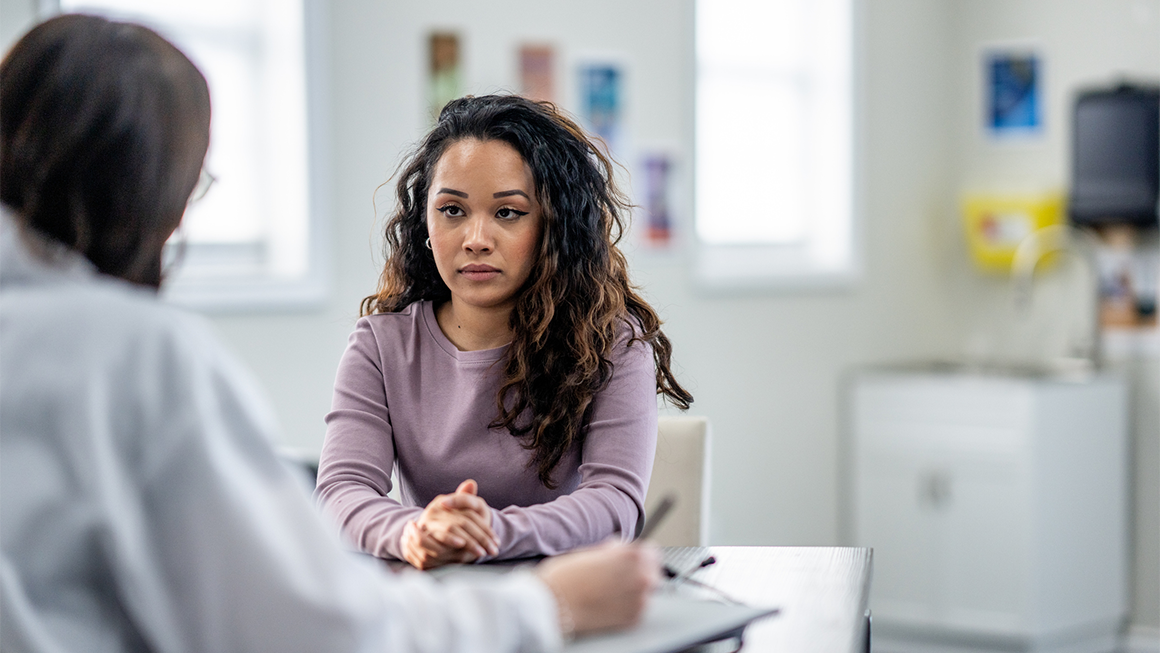 young woman of mixed race, sits with her female doctor as they discuss her health