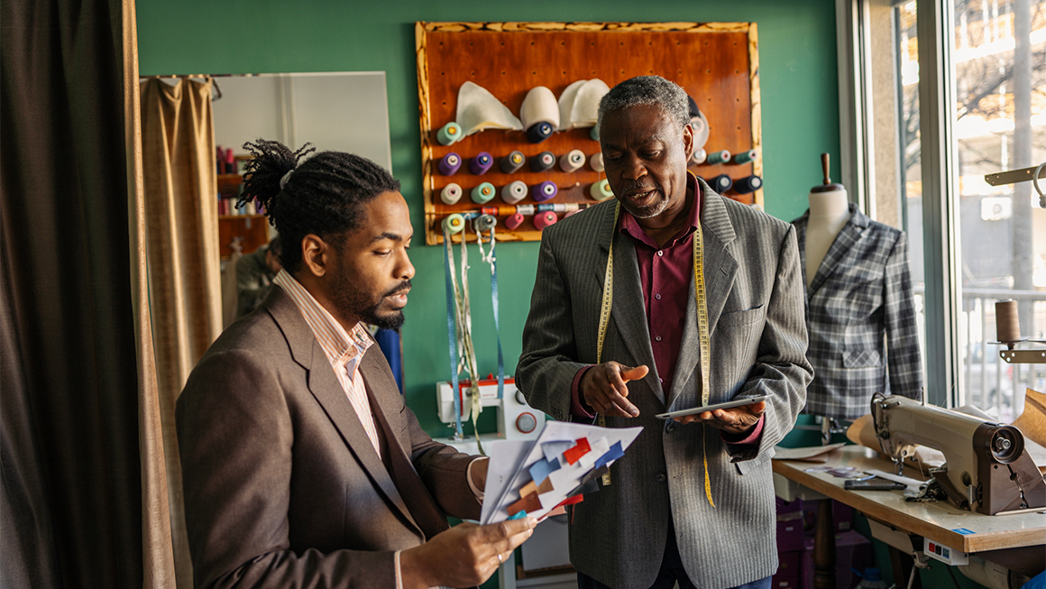 afrolatin senior tailor working with client in studio