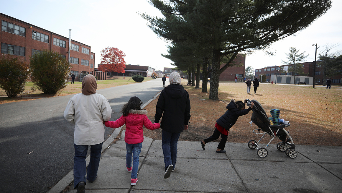 An Afghan refugee family walks past temporary housing in Liberty Village on December 2, 2021 in Joint Base McGuire-Dix-Lakehurst, New Jersey.