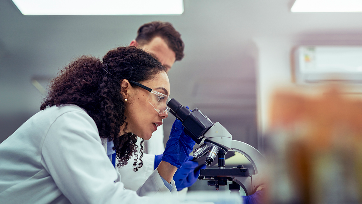 A scientist looking through a microscope.