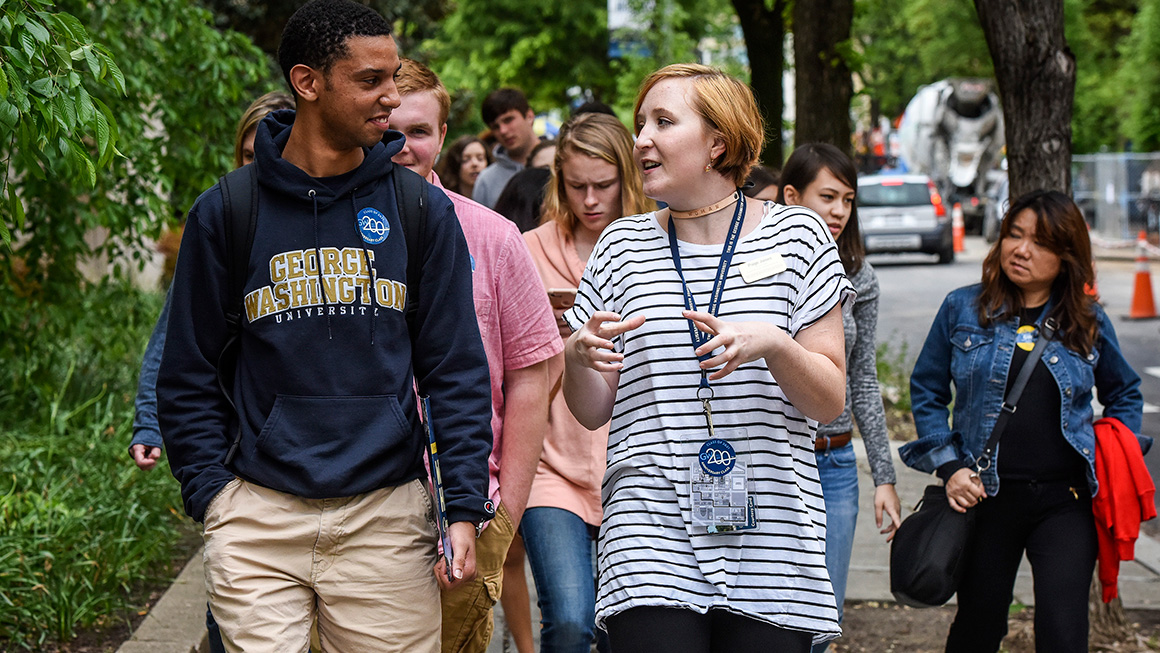 A grouo of college students walking down a street. 