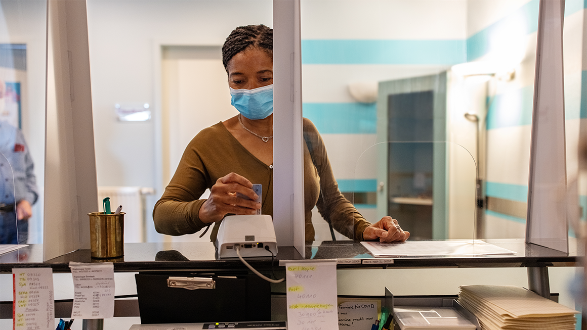 Woman wearing a mask at a reception desk.
