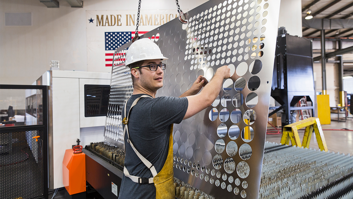 A person with a hard hat working at a factory.