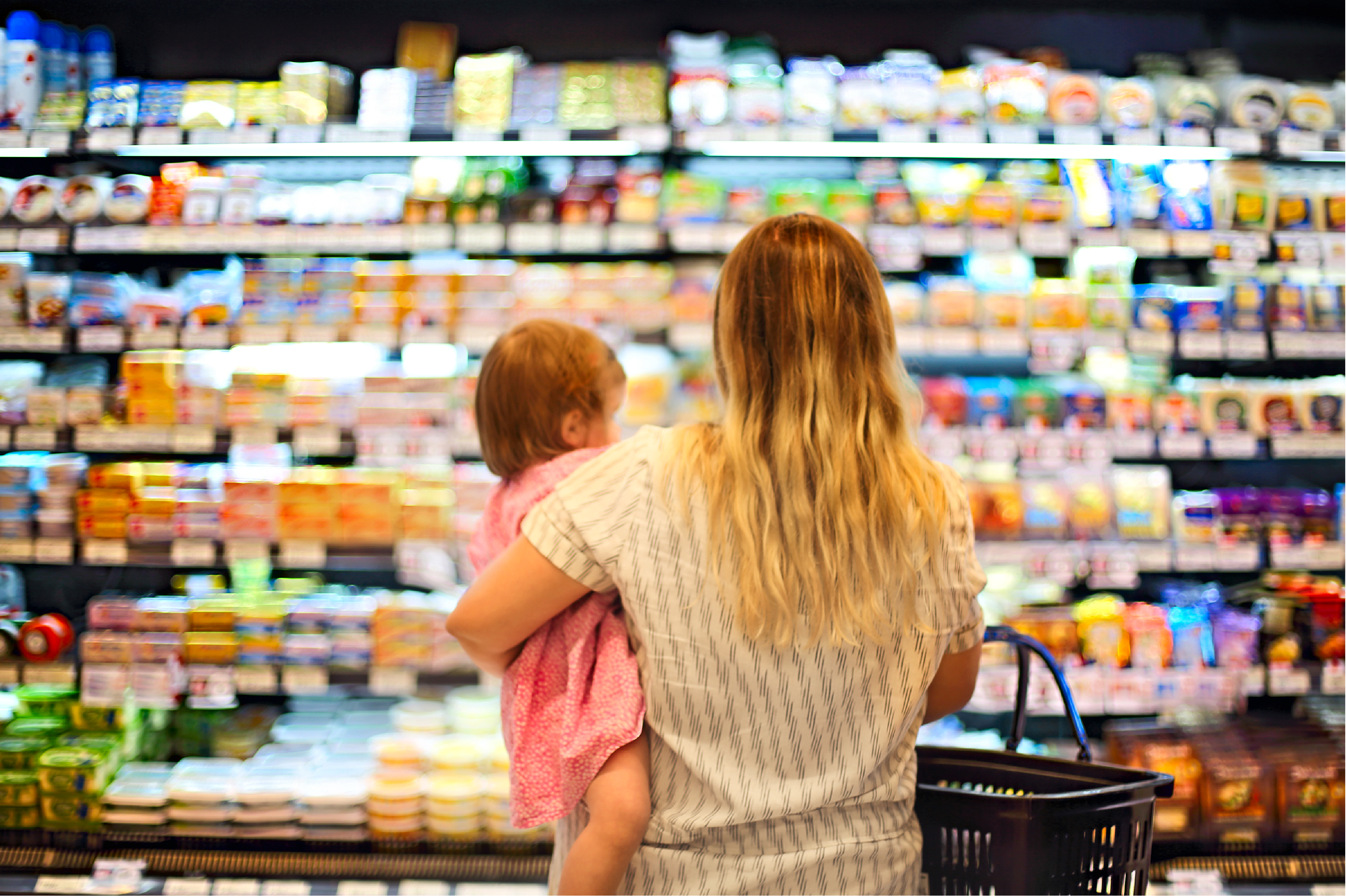 photo of woman standing holding child in front of grocery aisle