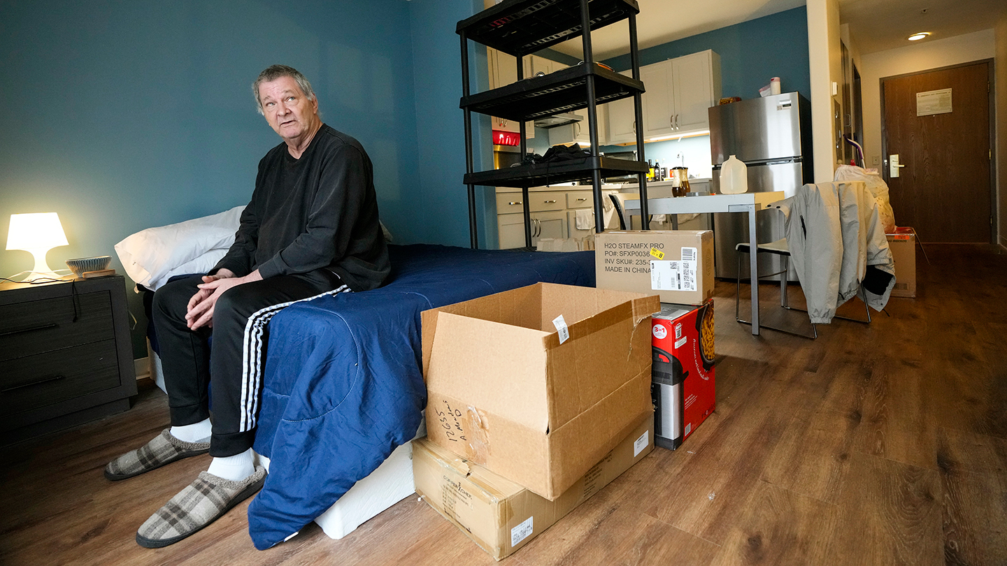 A man in a room with moving boxes. 