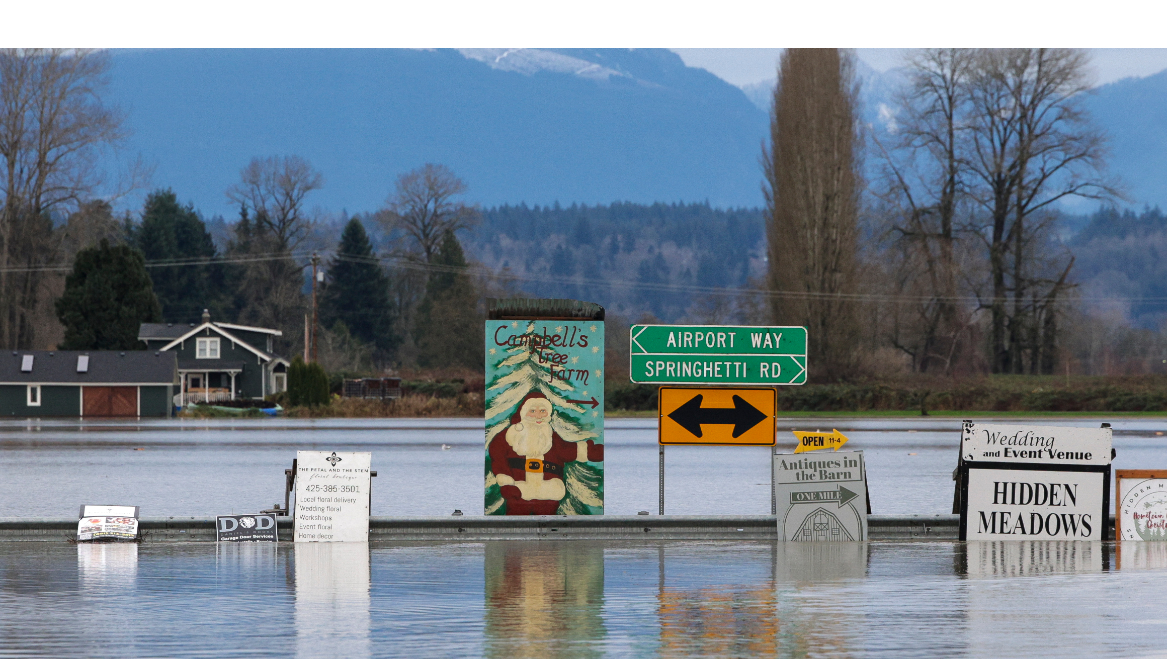 A sign for a Christmas tree farm is pictured as flood waters from the Snohomish River cover Marsh Road off State Route 9 in Snohomish, Washington