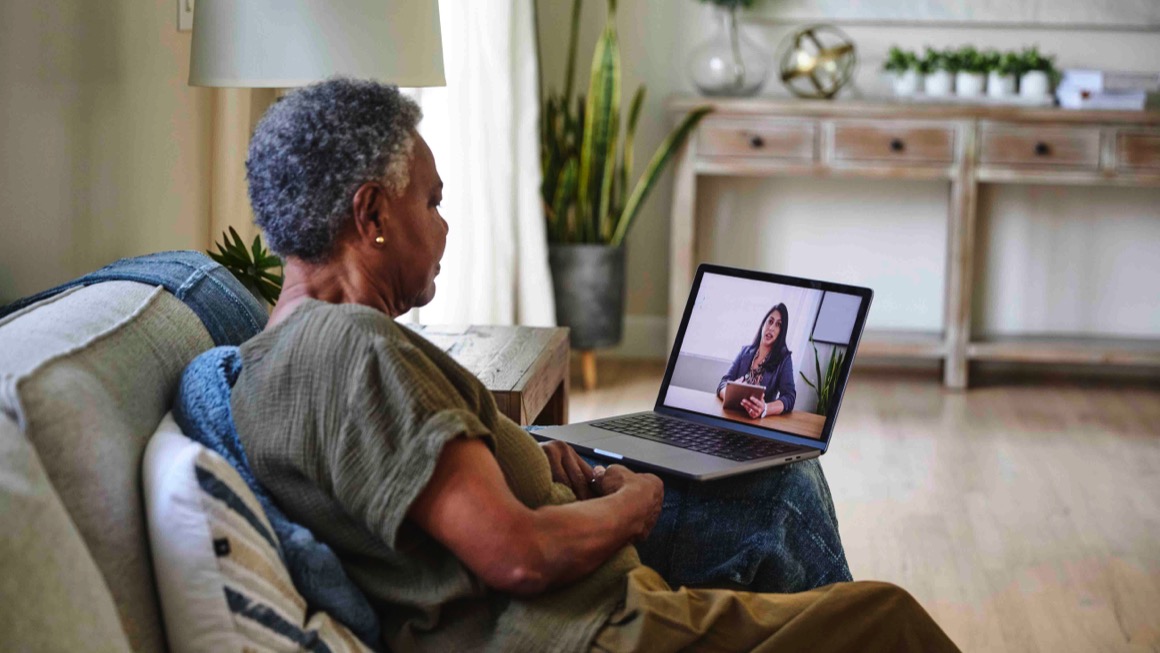Photo of an older Black woman on a video call with a health care provider.