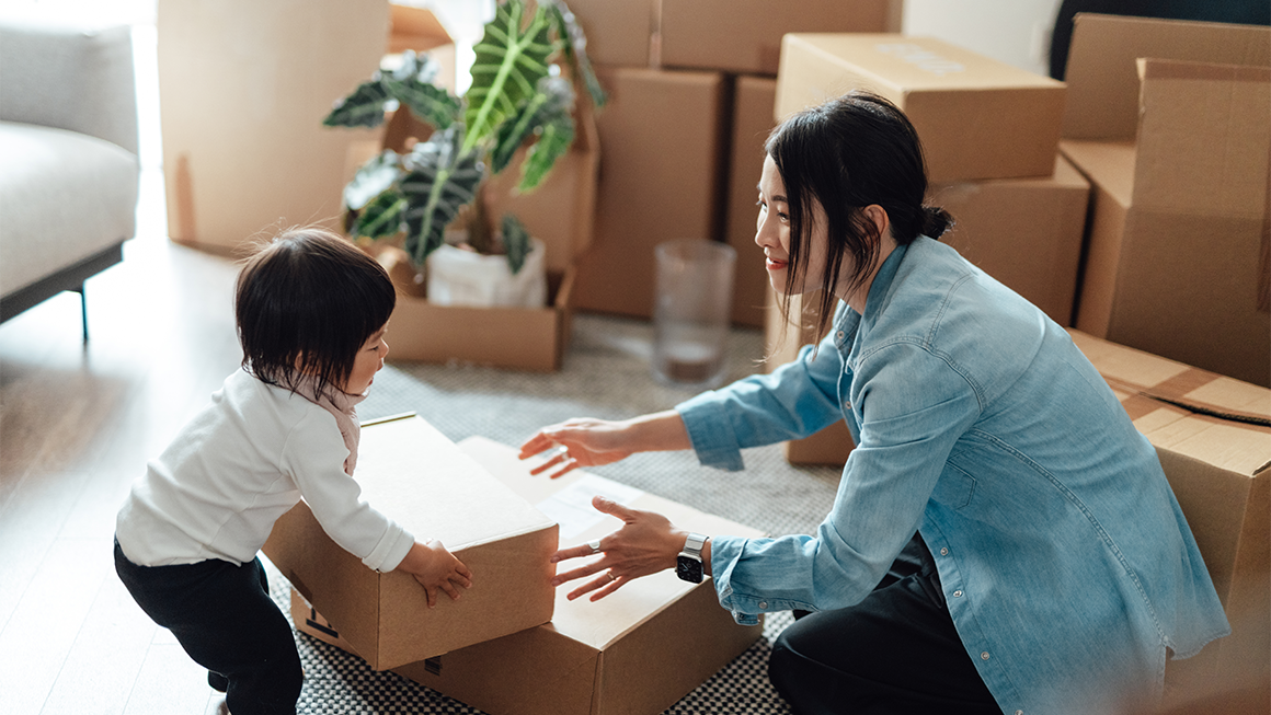 Photo of a toddler helping her mother pack a box.
