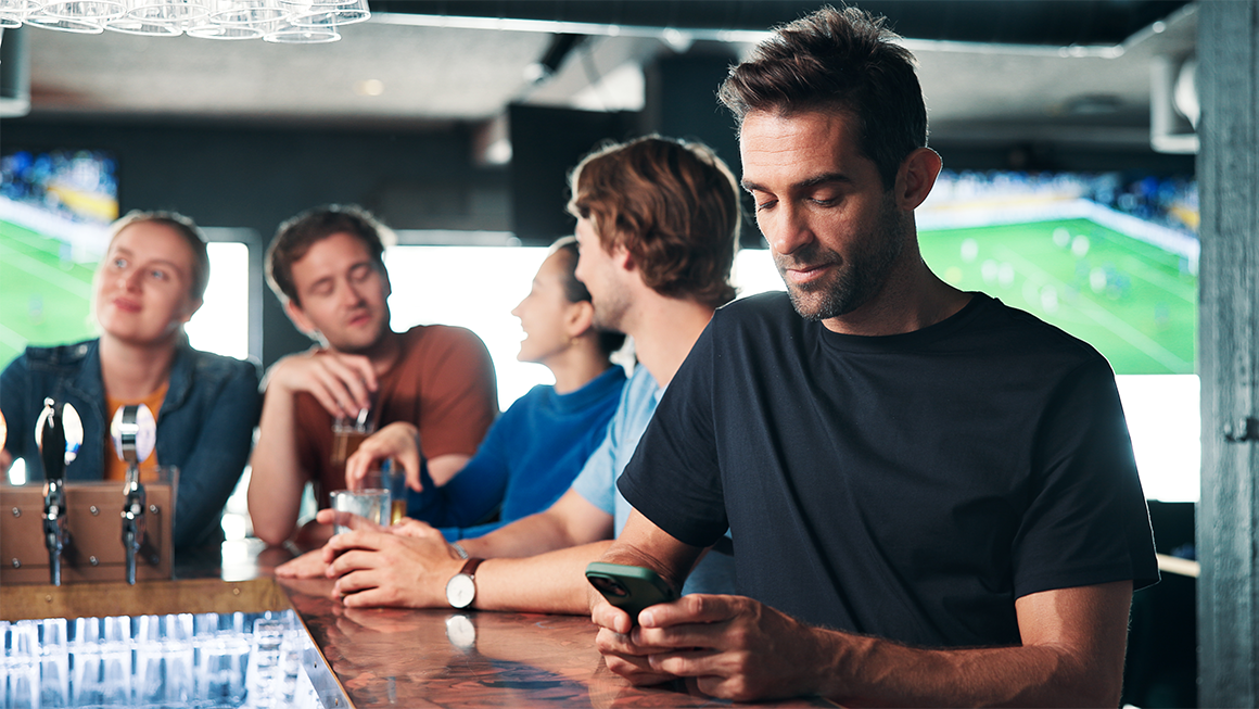 man browsing on smartphone in a pub and sports betting for entertainment