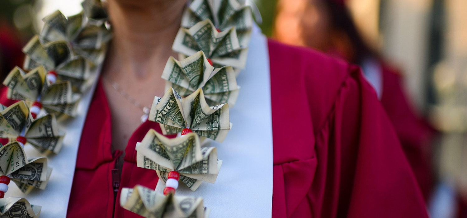 A graduate wears a lei made of dollars