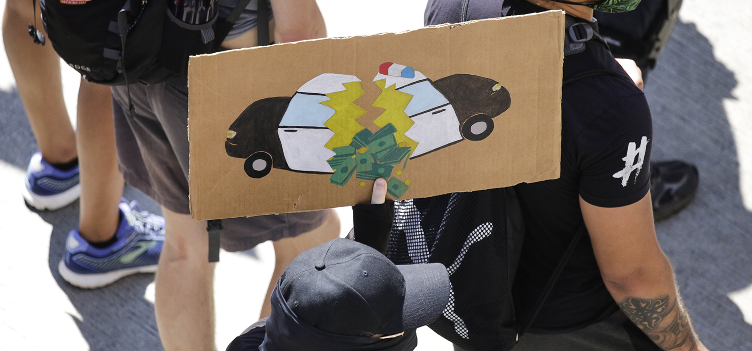 A protester carries a sign during a "Defund the Police" march from King County Youth Jail to City Hall in Seattle, Washington on August 5, 2020. (Photo by JASON REDMOND/AFP via Getty Images)