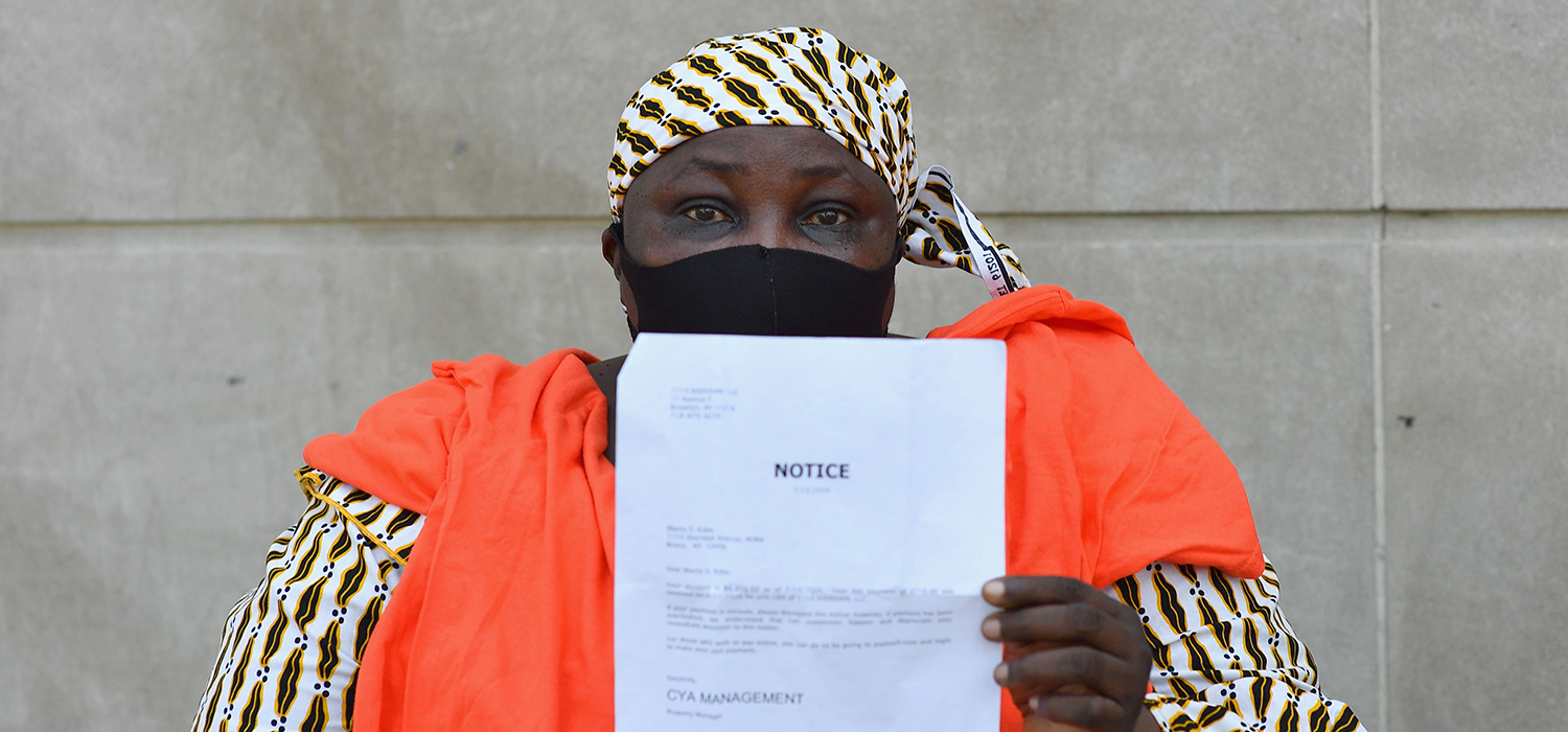 Woman holds up a notice to pay an outstanding rent balance