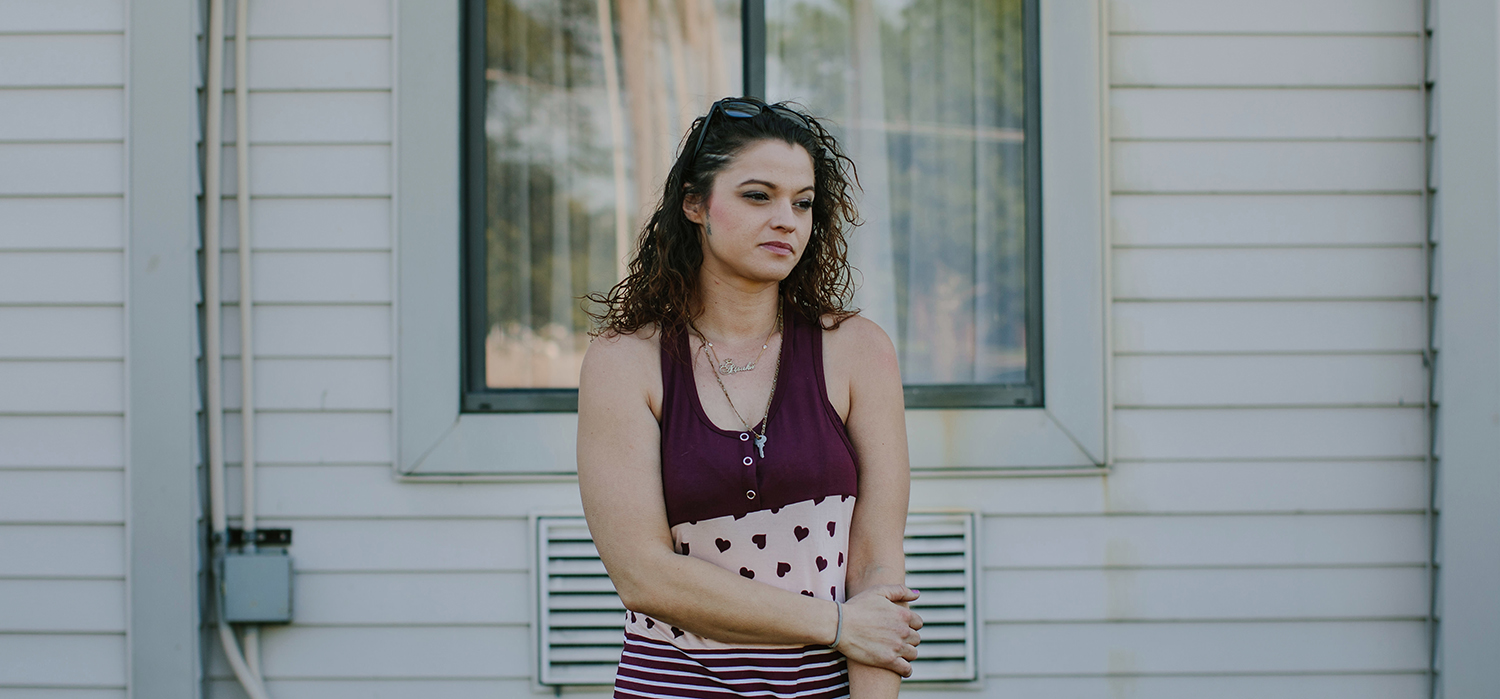Woman stands in front of her house