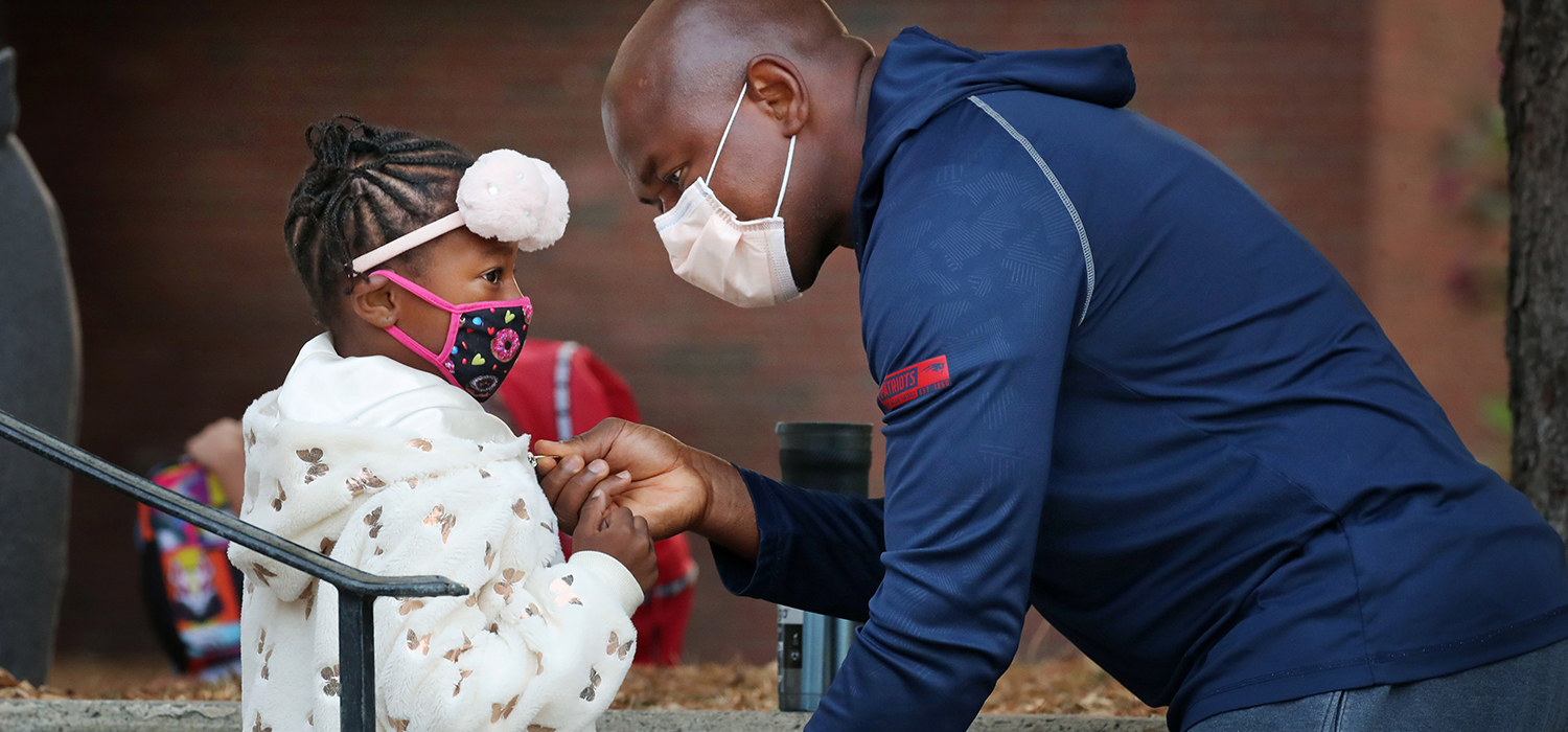 A father helps his daughter with her jacket while dropping her off for her first day of 1st grade at the Lincoln-Hancock Community School in Quincy, MA on September 17, 2020.