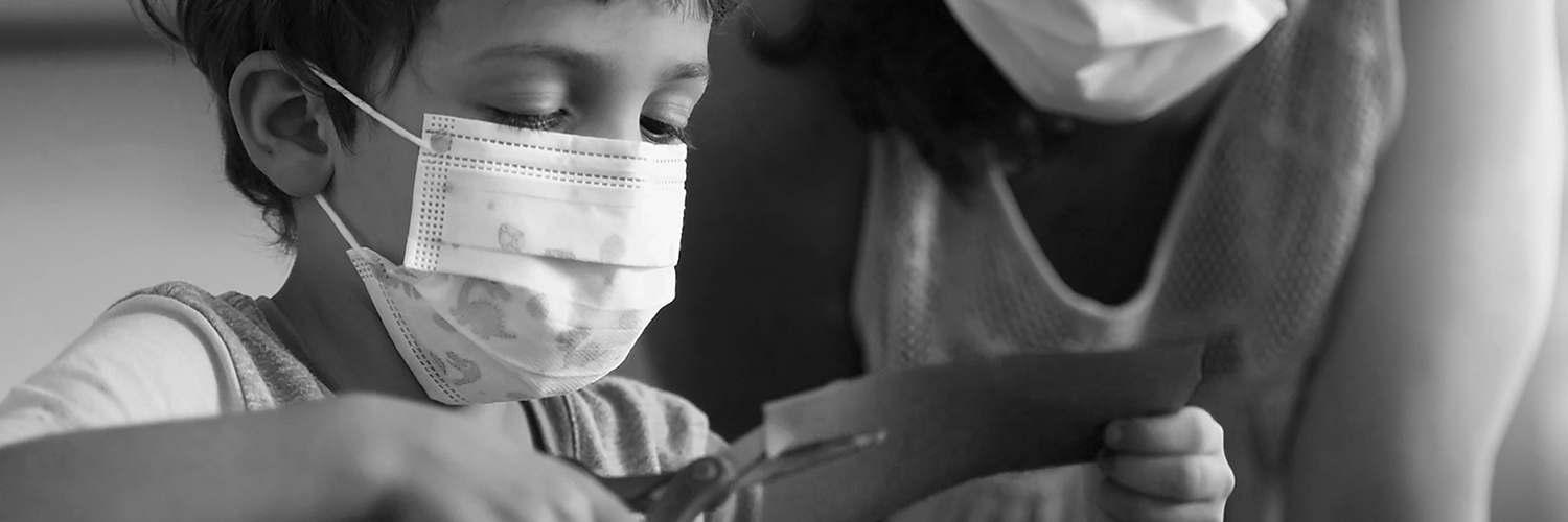 Child does crafts while wearing a mask