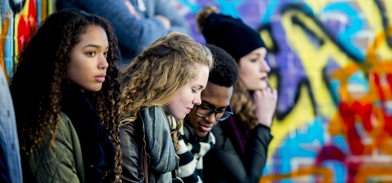 Teenagers hang out beside a mural