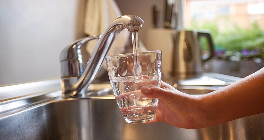 Person filling glass from faucet