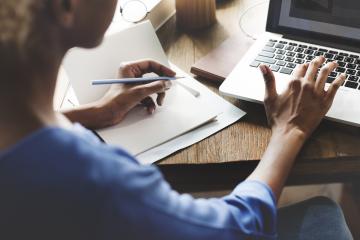 Women typing on a computer while at a desk.