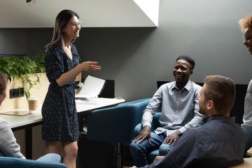 Diverse staff gathered together in co-working space listening to each other.