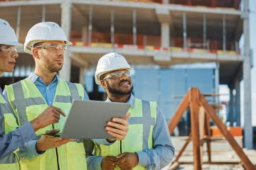 Diverse Team of Specialists Use Laptop on Construction Site
