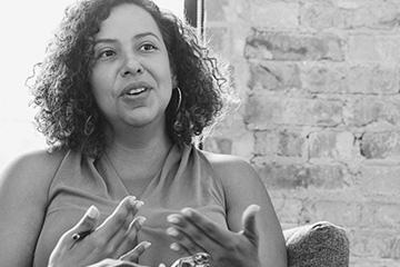 A woman speaks in front of a window