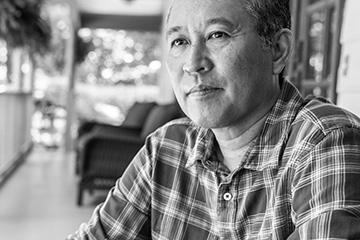 A man sits on his porch looking pensively. 