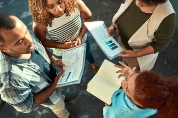 Team, business people and discussion in top view with data, kpi analysis and metrics in creative startup. African group, planning and brainstorming ideas with graph, stats and social media marketer
