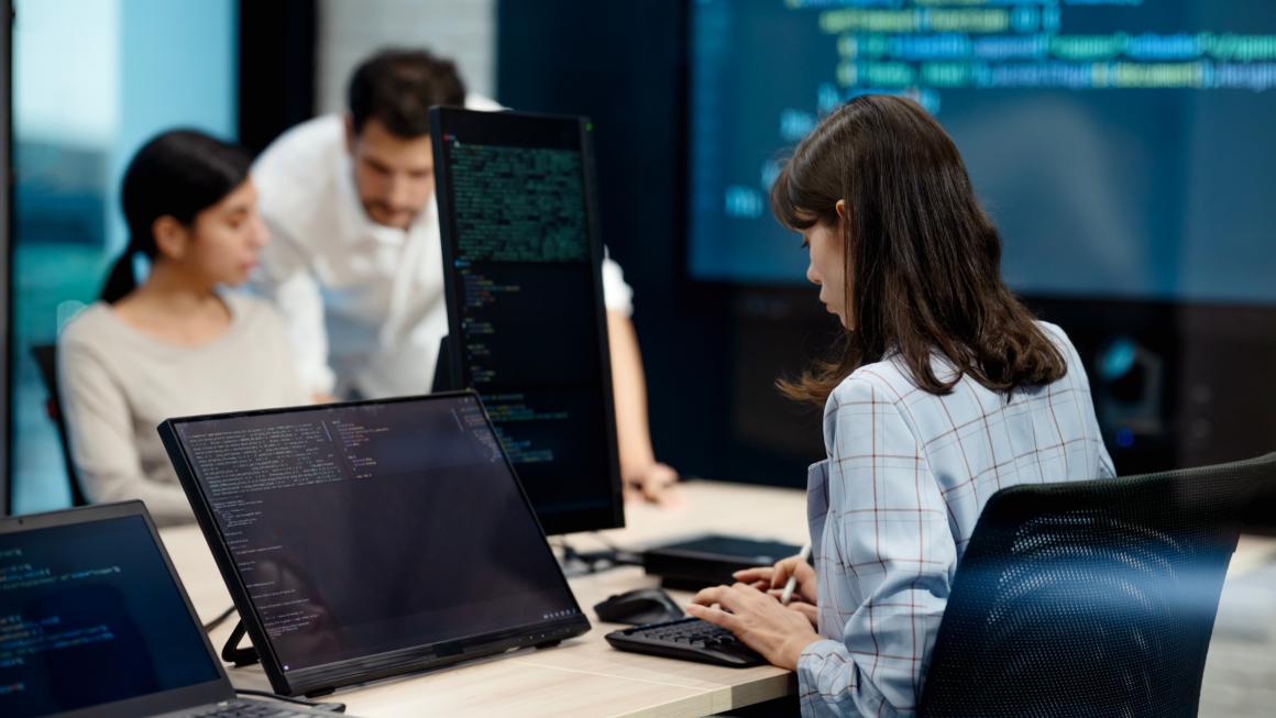 People working at computers with coding screens.