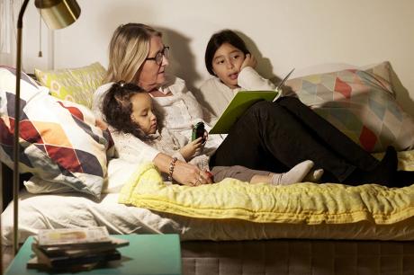 Woman reading to two young girls. 