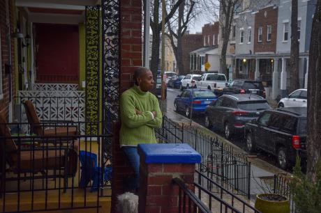 Woman stands on the front porch of her home.