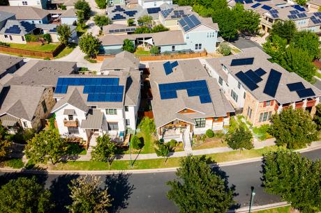 Aerial shot of large green neighborhood with homes with solar roof panels