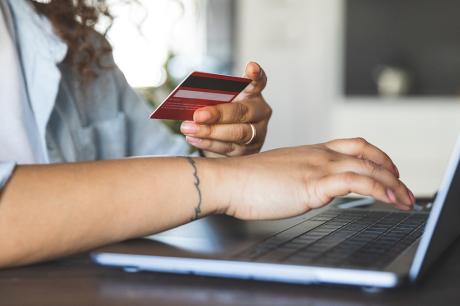 A woman using a laptop with her credit card in hand.
