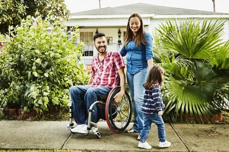 A man in a wheelchair with a woman and child.
