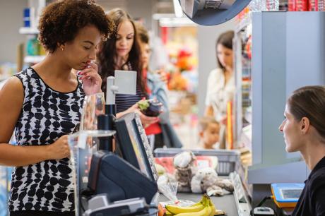 Woman at a grocery store checking out at cash register. 