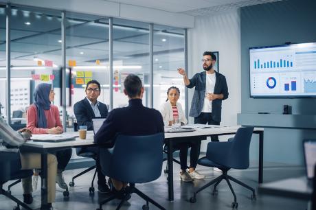 A man presenting graphs to a group of colleagues. 