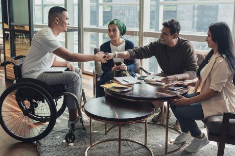 A man in a wheelchair meeting up with three more people. 