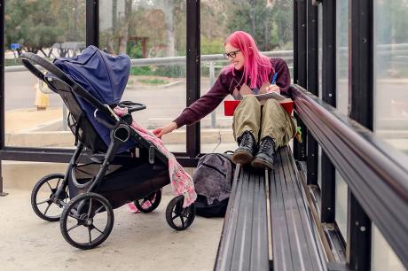 A mother and her baby at a bus stop. 