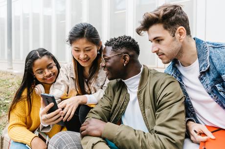An image of a group of young adults looking at a cellphone. 