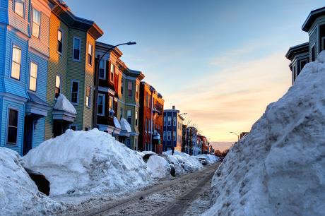Row of townhomes with snow in the sidewalks. 