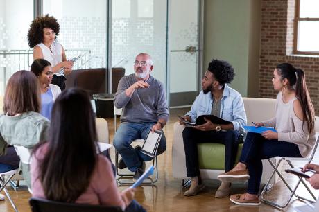 A group of people seated in chairs in a circle. 