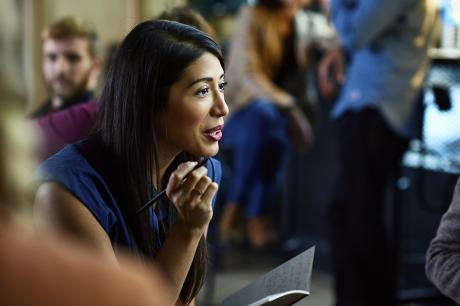 A woman taking with notebook and pen in hand.