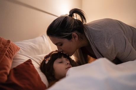 A women kissing her child on her forehead.