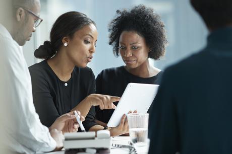 Two women working and looking at a tablet.