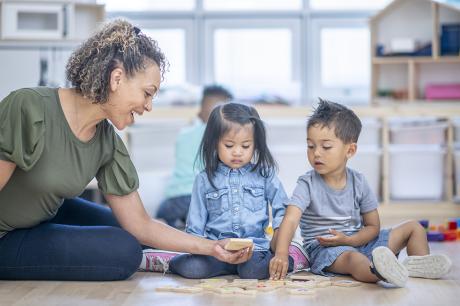 A teacher playing with yound children.